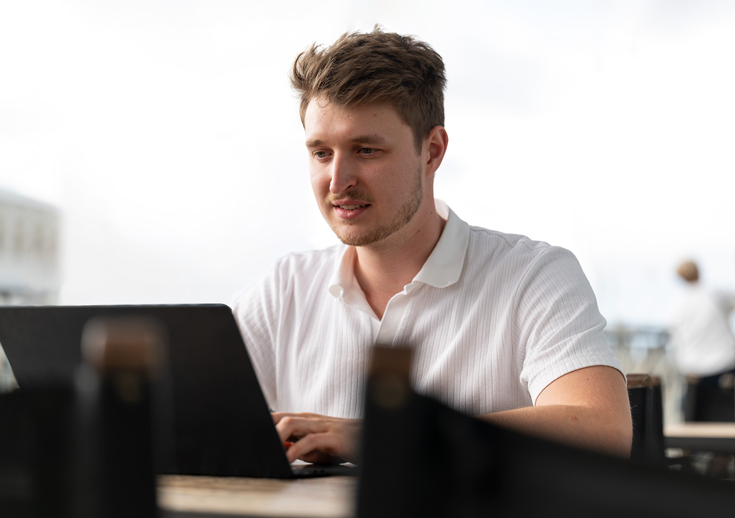 Manuel sitzt konzentriert arbeitend an einem Laptop 