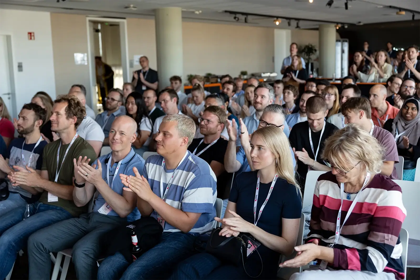 Verschiedene Menschen, die in einem modernen Konferenzraum einer Veranstaltung aufmerksam applaudieren.