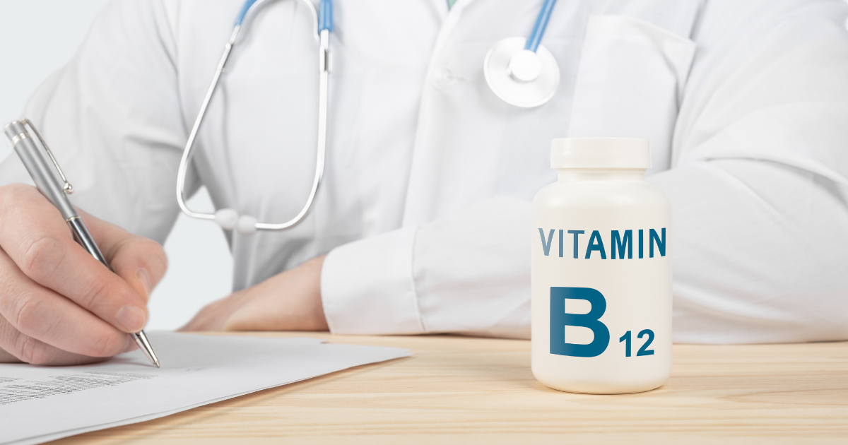 Doctor in a white coat writing notes at a desk beside a bottle of Vitamin B12 supplements