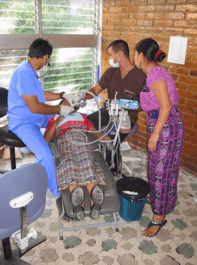 A group of people standing around a woman in a hospital bed.