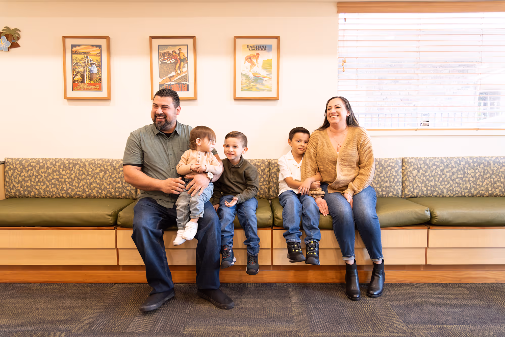 A family sitting on a couch in a waiting room.