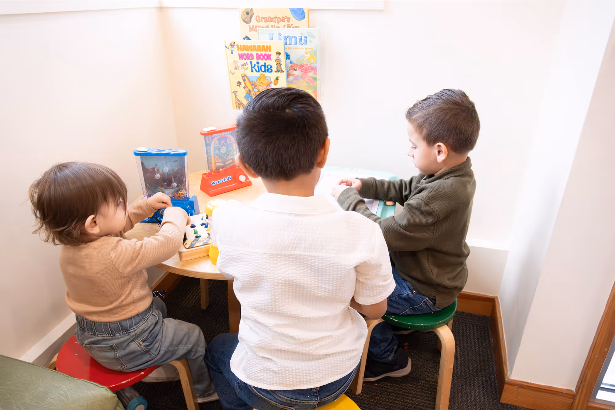 Three children sitting at a table playing with toys.