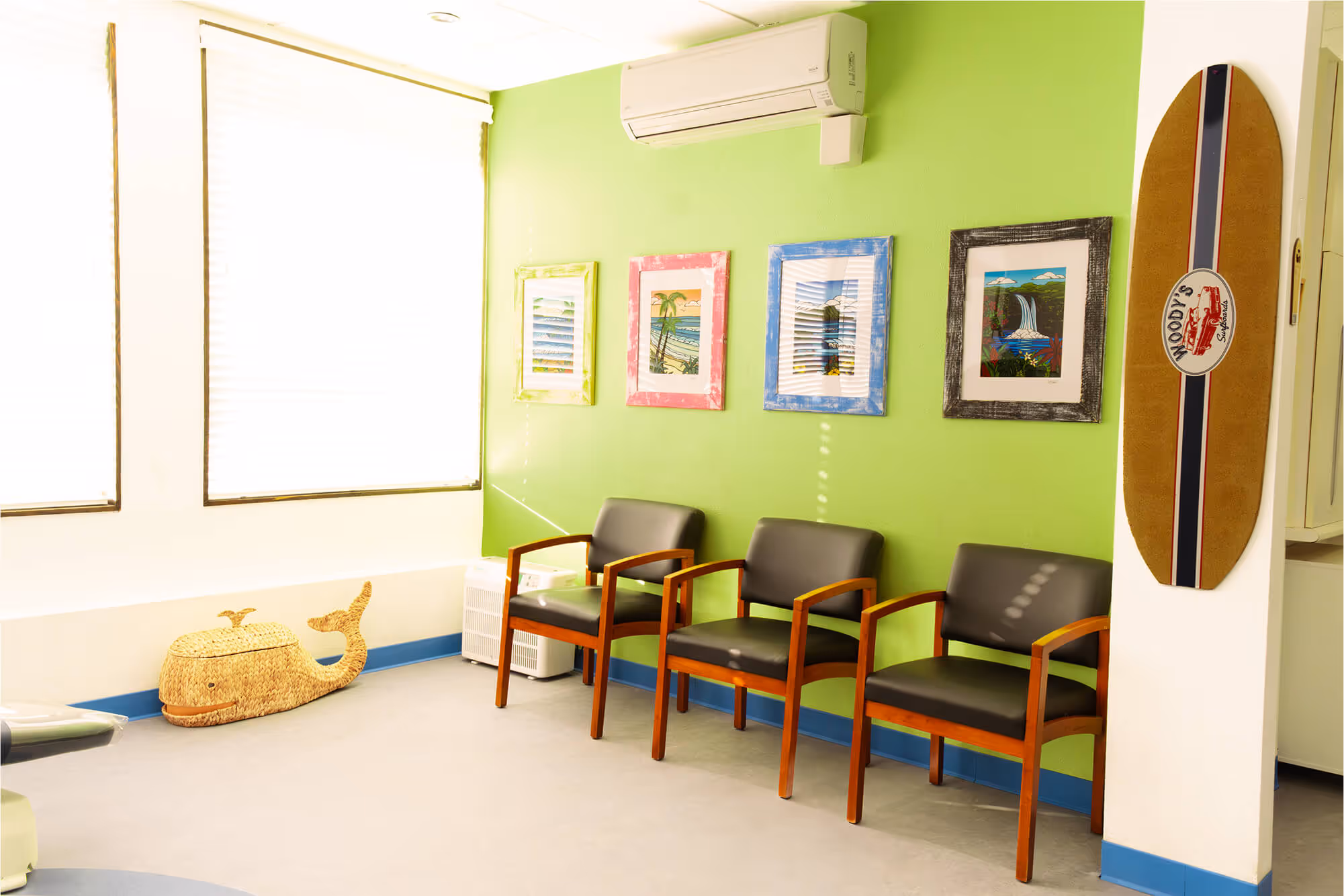 A waiting room with four chairs and a surfboard on the wall.