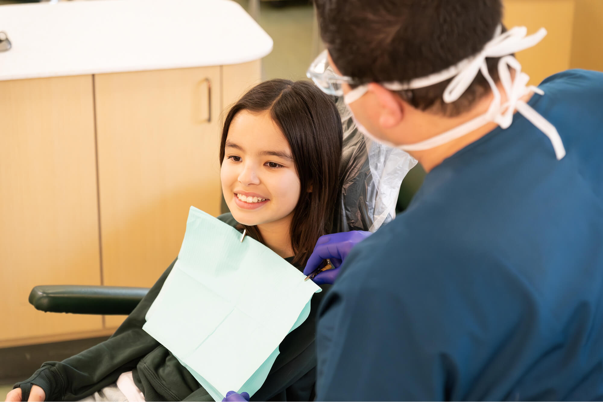 A young girl sitting in a dentist chair.