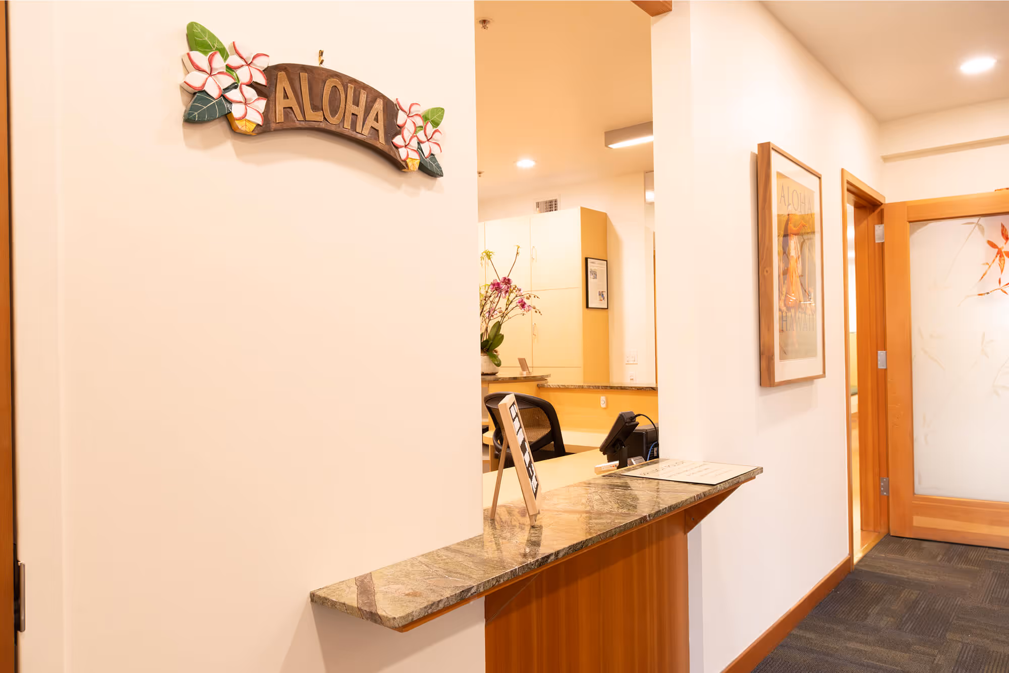 A hallway with a counter and flowers on the wall.