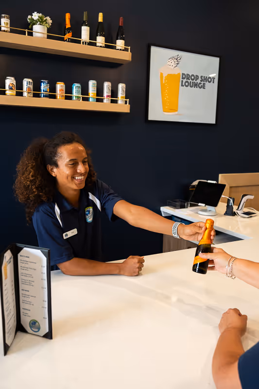 A bartender serving a beverage to a customer at the Drop Shot Lounge.