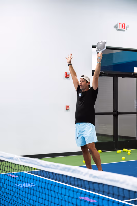 A pickleball instructor celebrating a great shot by their student.