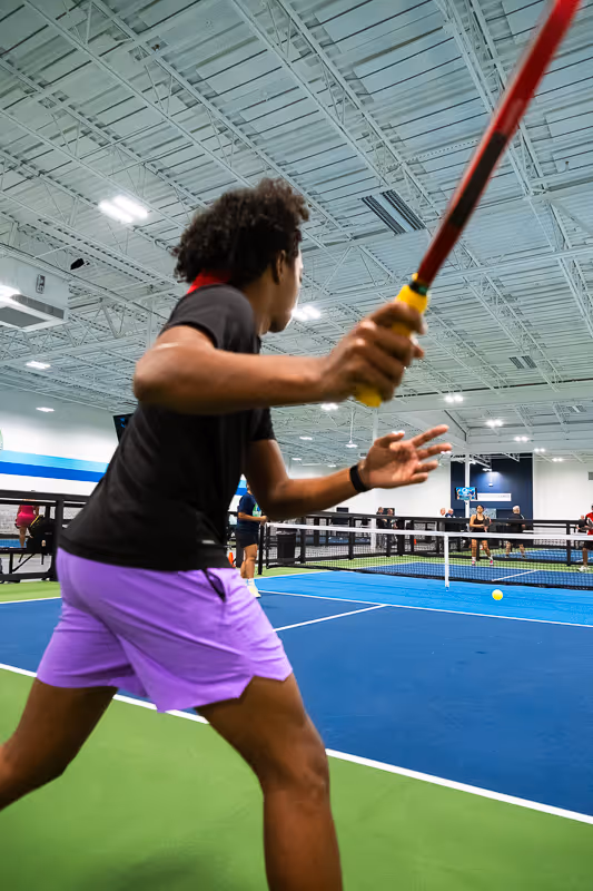 A pickleball player preparing to strike a ball.