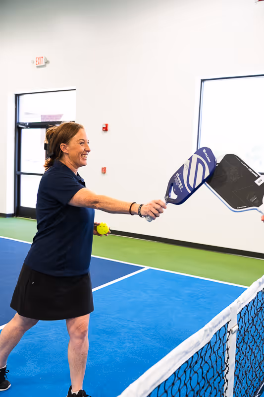 A pickleball player dinking their paddle with another pickleball player.