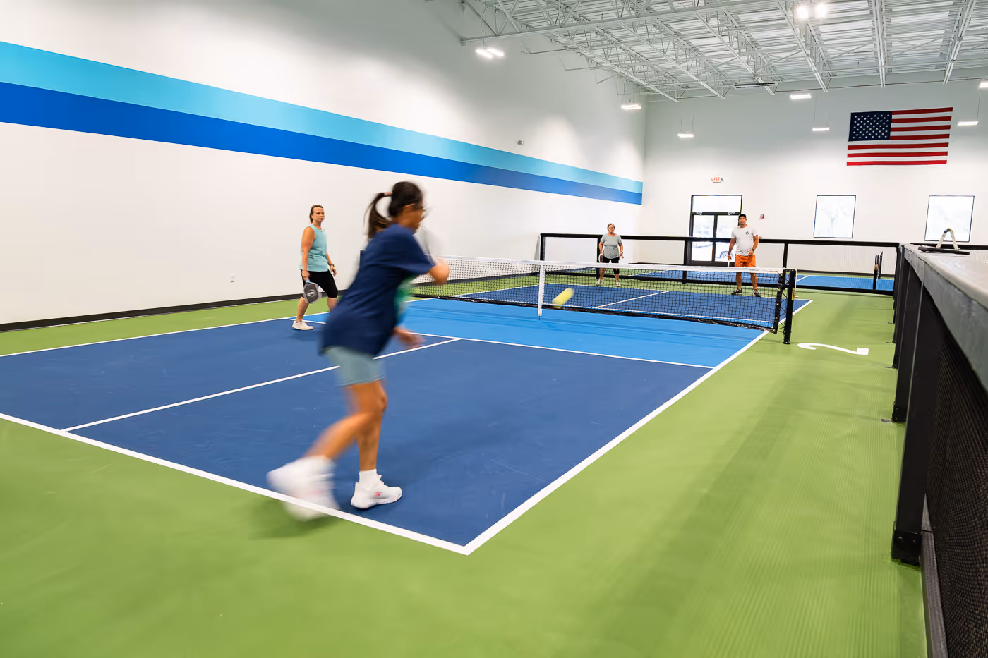 A woman hitting a return of serve in a game of pickleball.