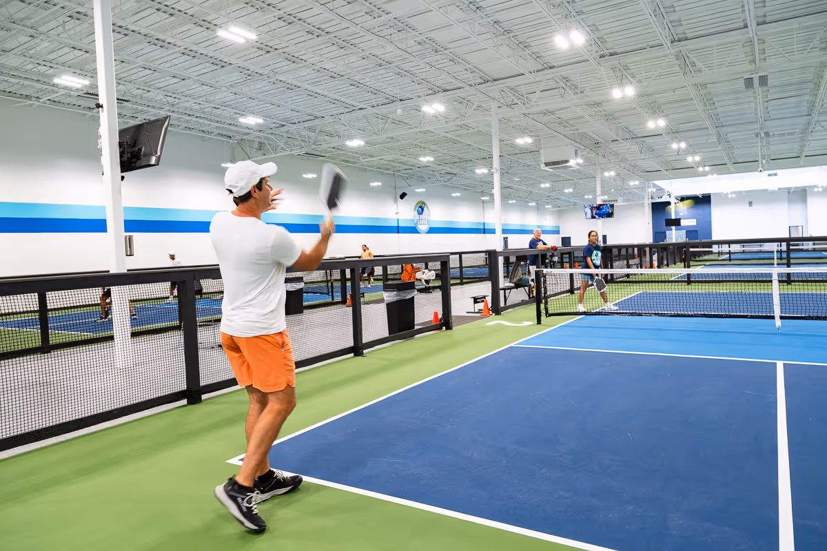 A pickleball player swinging a pickleball paddle.