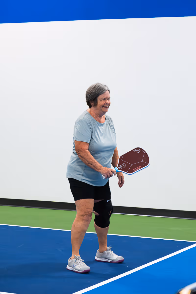 A smiling pickleball student receiving a lesson.