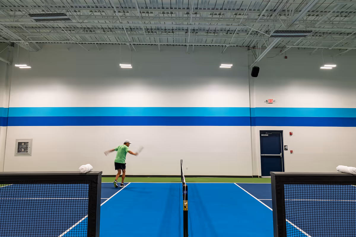 A man running on a pickleball court.
