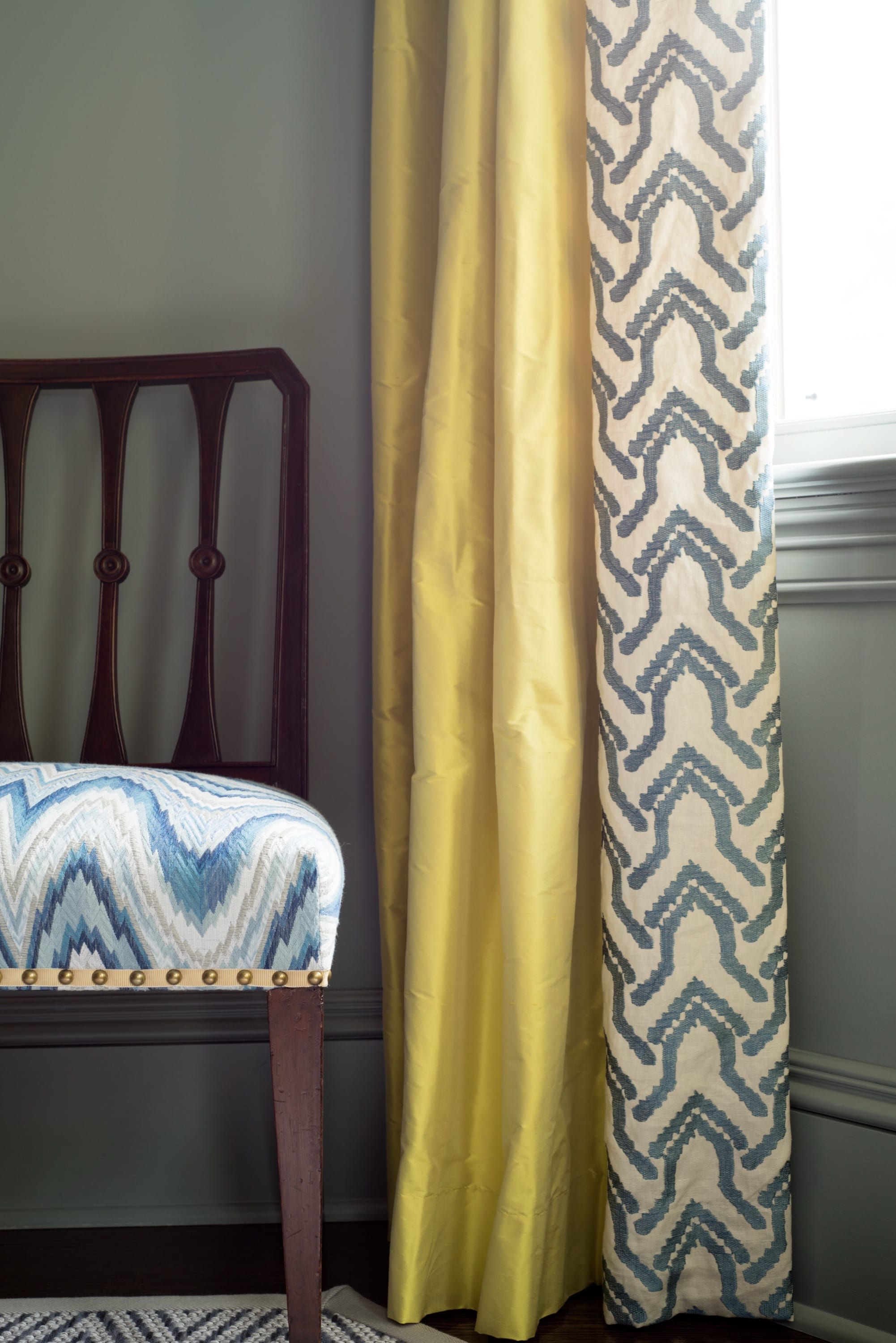 Bedroom corner with patterned curtains and bed.