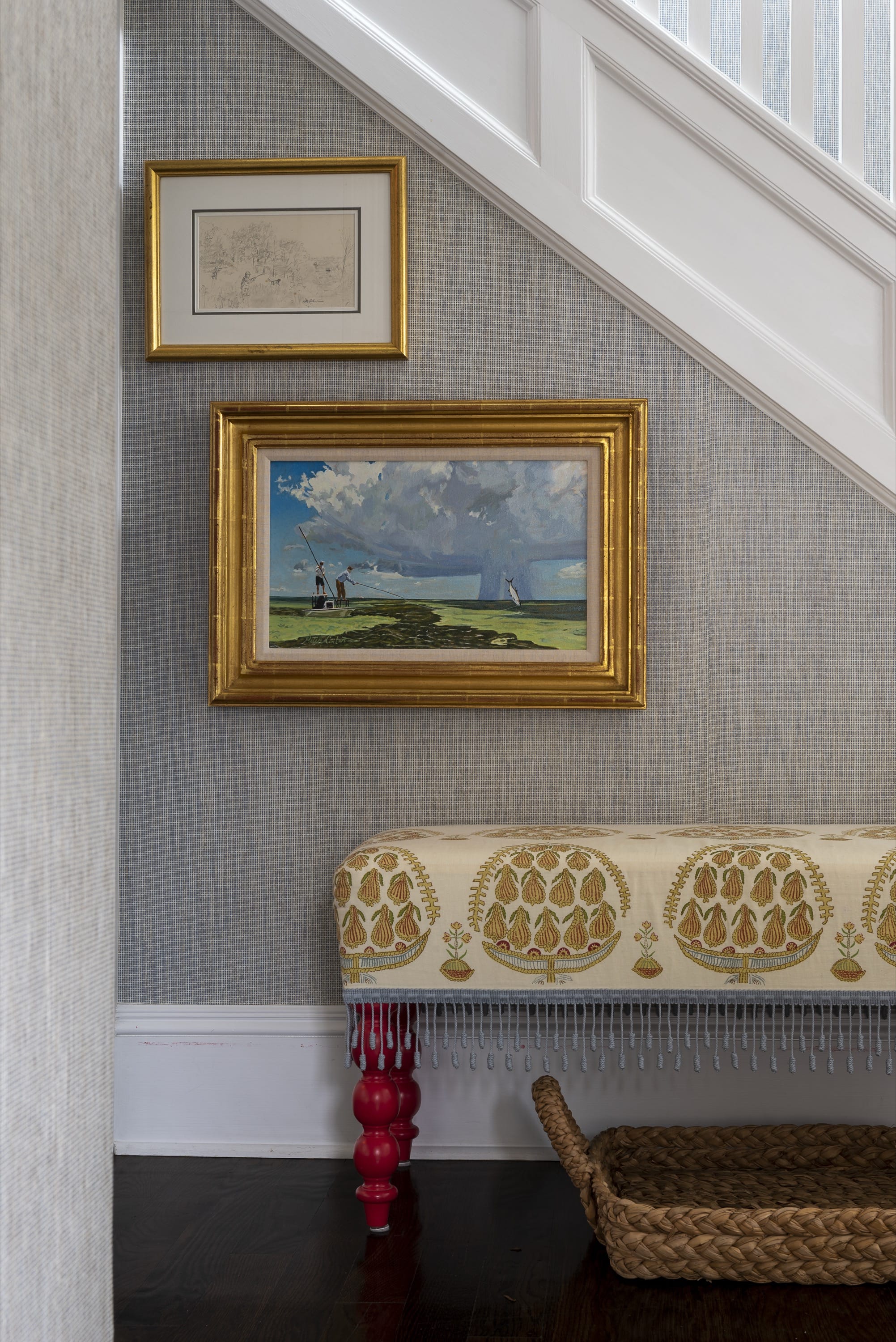 Staircase wall with framed artwork and bench.