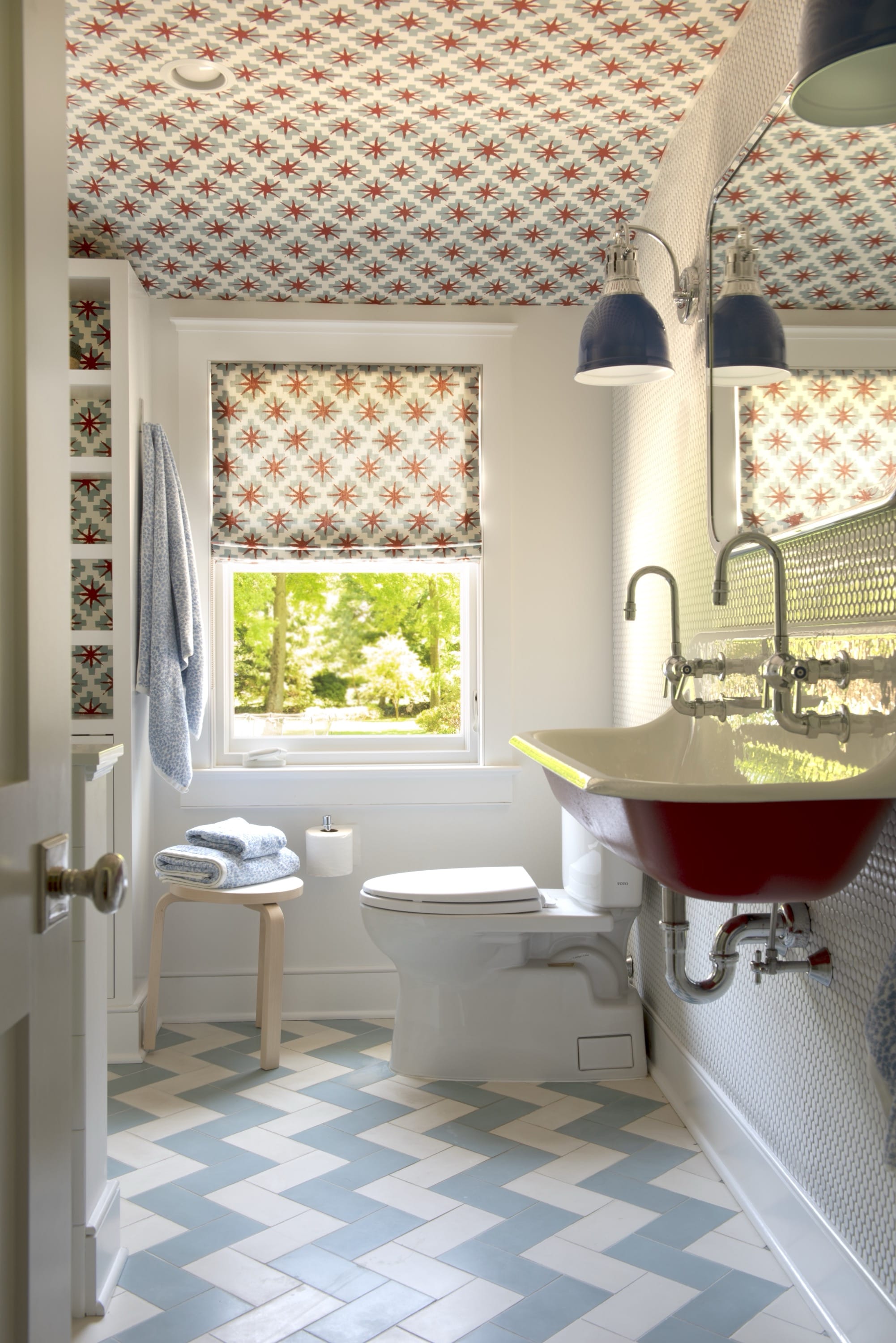 Boy’s bathroom with red sinks and blue floor tiles.