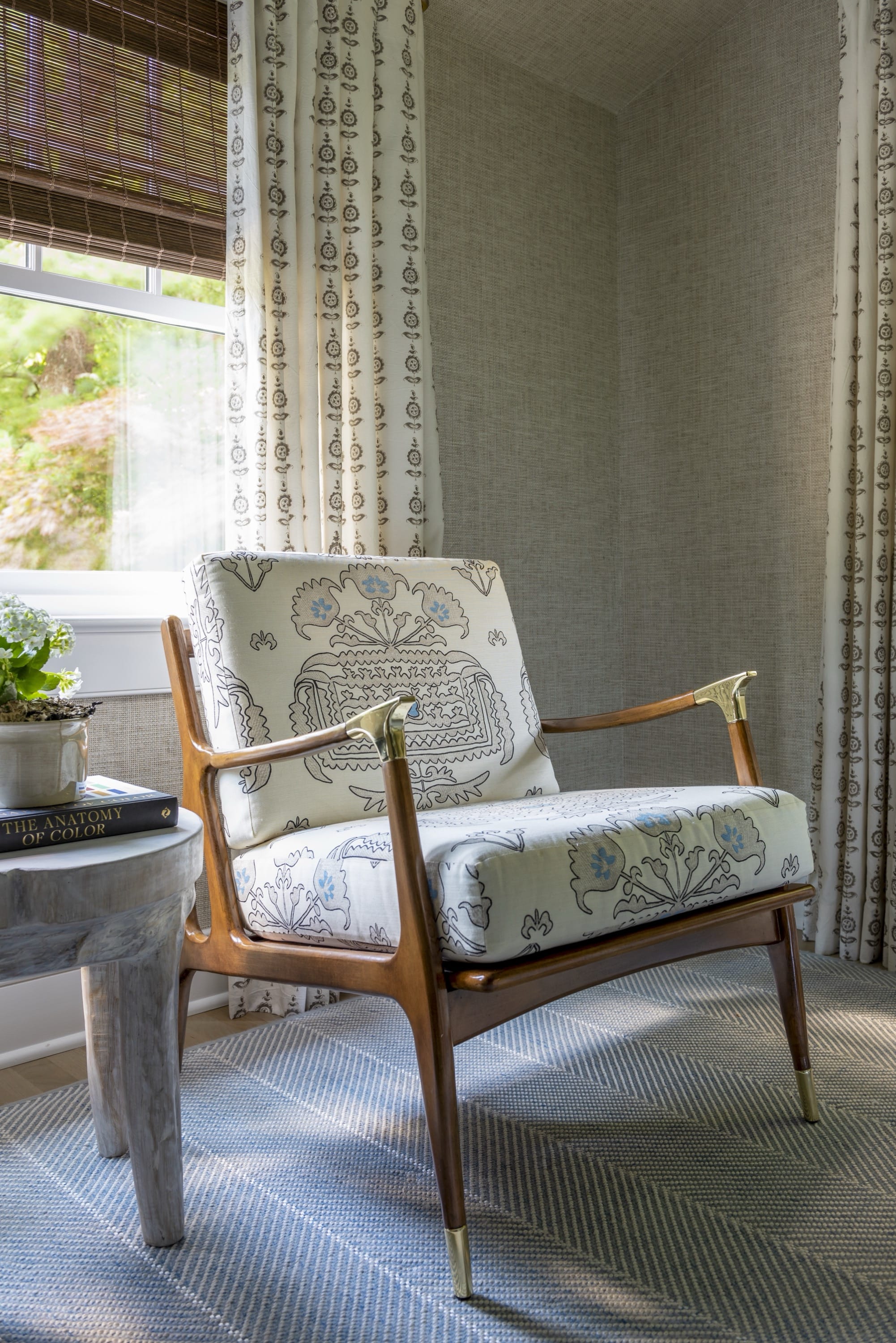 Wooden armchair beside window with checkered drapes.