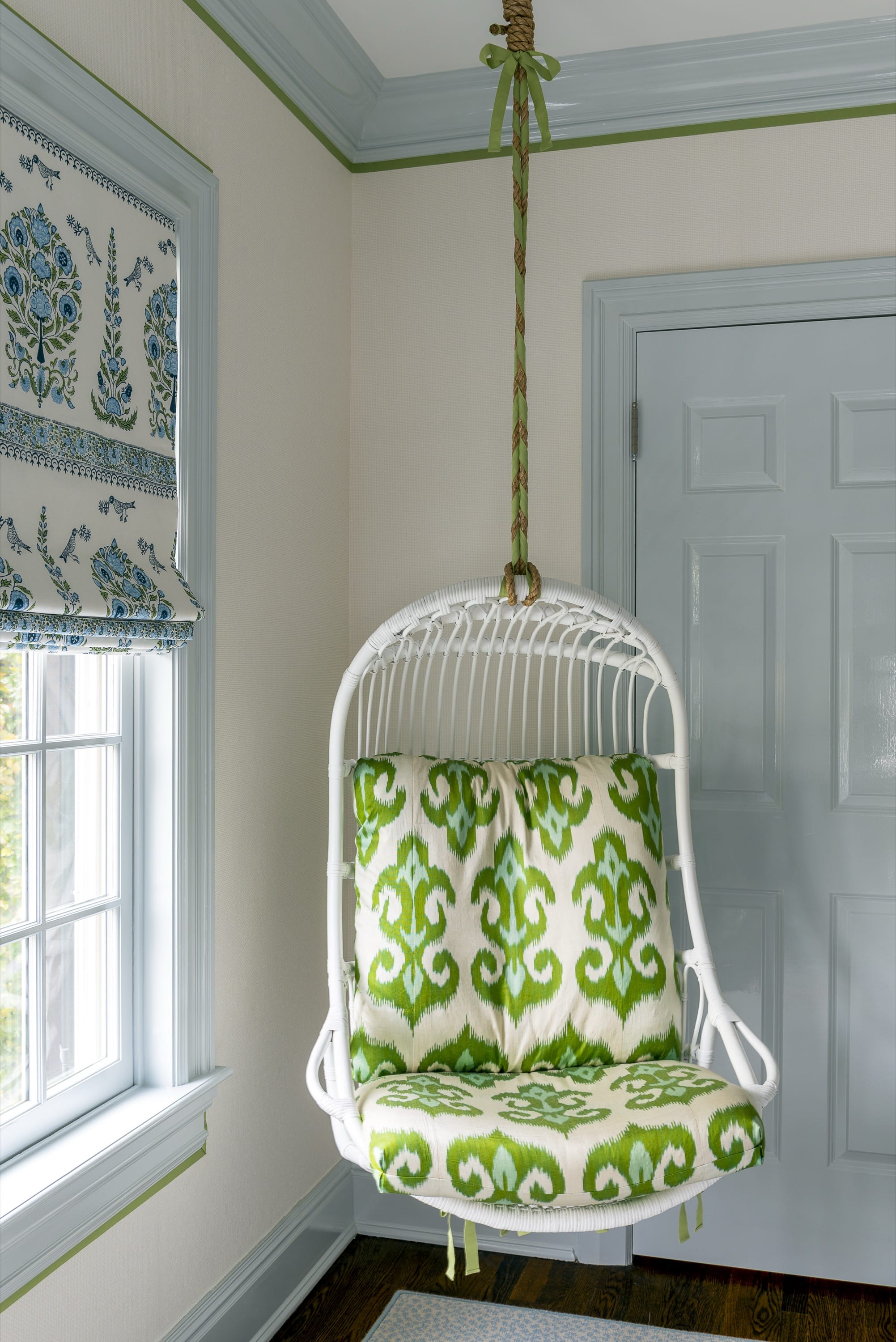 Green and white hanging chair by window.