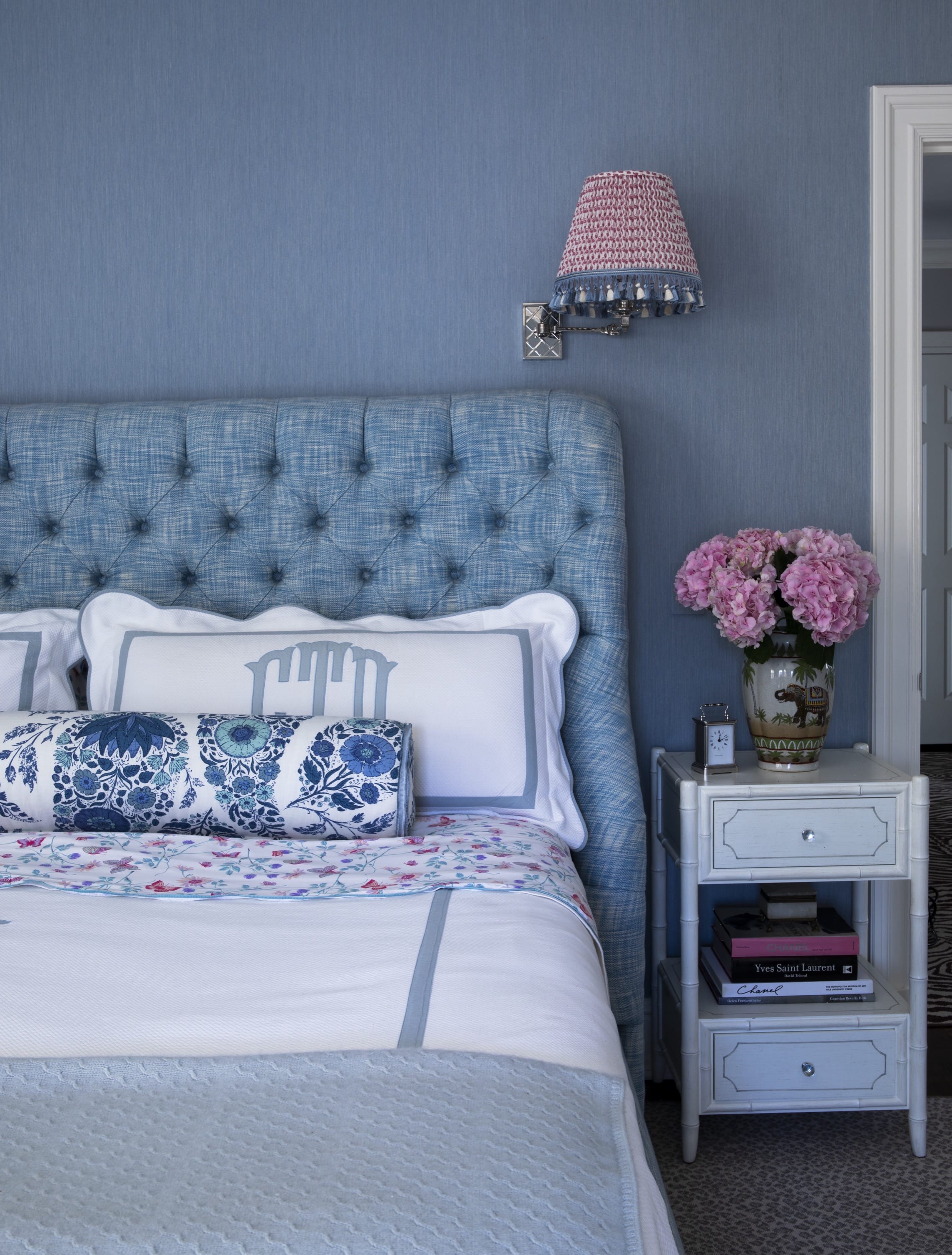 Bedroom with tufted blue headboard and side table.