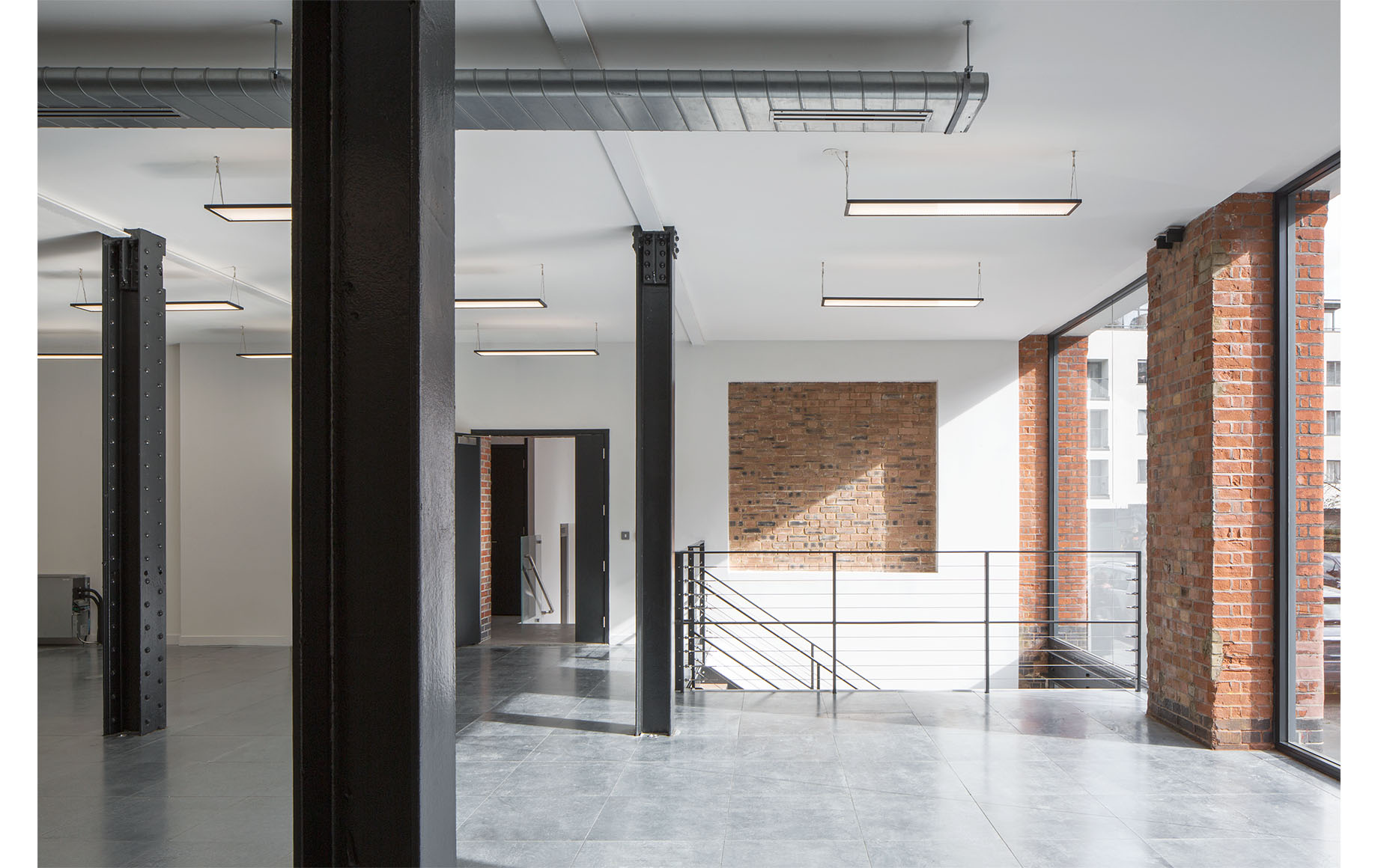 Industrial interior of a project, with black metal columns, with brick pillars towards the external facade of the building.