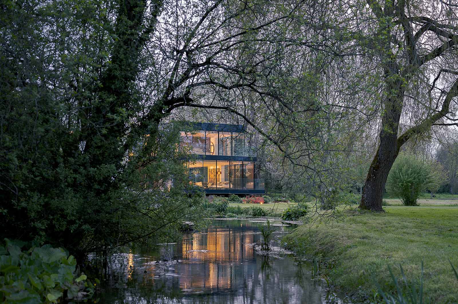 Knighton Mill, a house project set by a small body of water. Photo is showing the project in the distance, in between trees. 