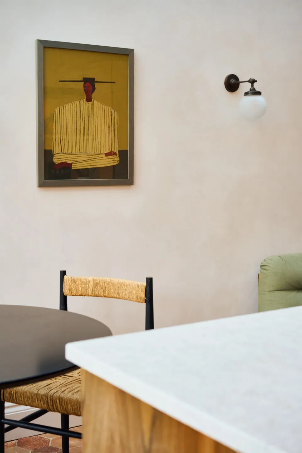 Zoomed in photo of a dining area designed by Louise. The focus is on the materiality, colour tones and how those come together in furniture, wall paint, surface and painting on the wall. 
