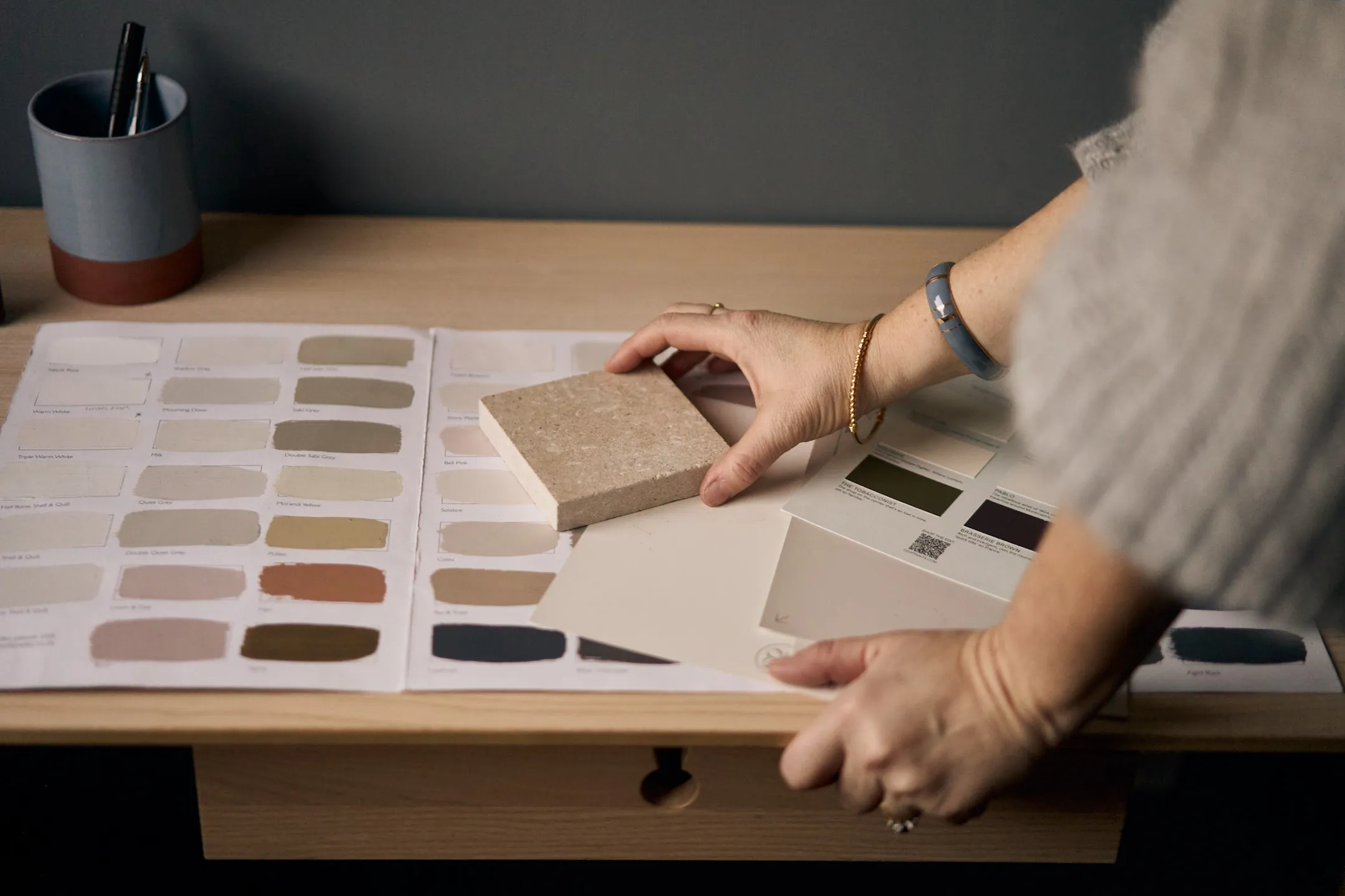 Zoomed in photo of Louise working through paint samples and pairing them to a chosen tile. The scene is set on a desk.