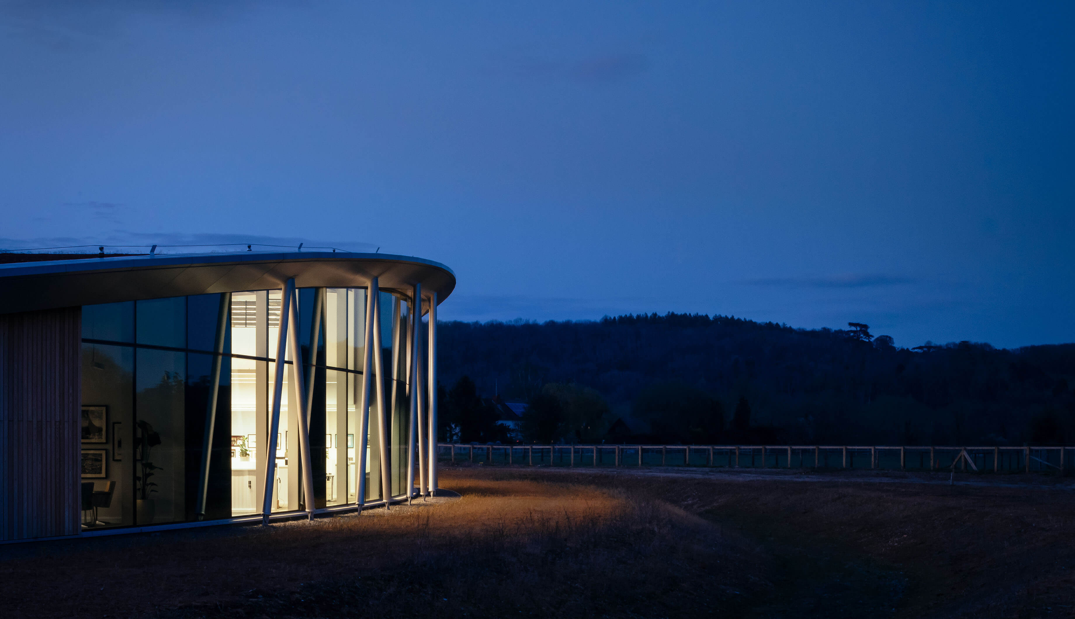 Photo of the external facade of the building in the evening, dark blue background of the sky against well-lit interior of the building