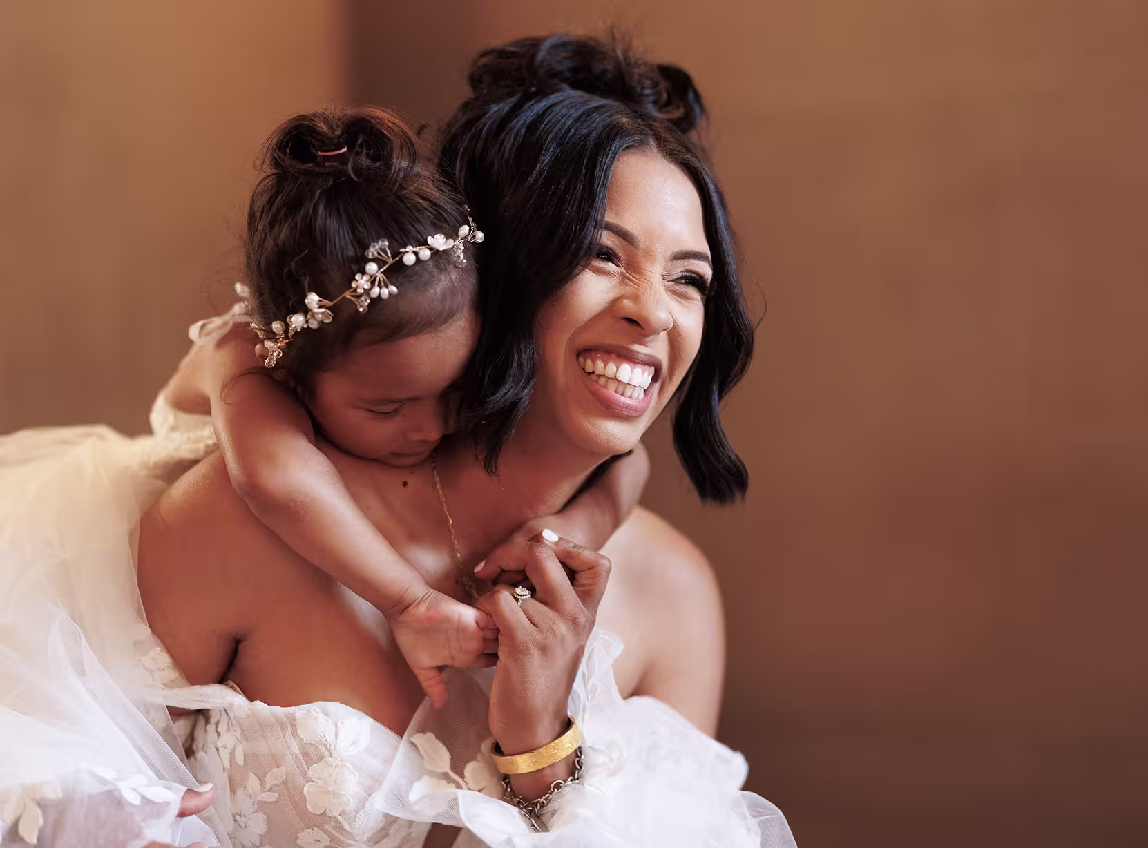 Bride smiling and holding a young flower girl on her back during a joyful moment at San Francisco City Hall, soft natural light and elegant wedding details