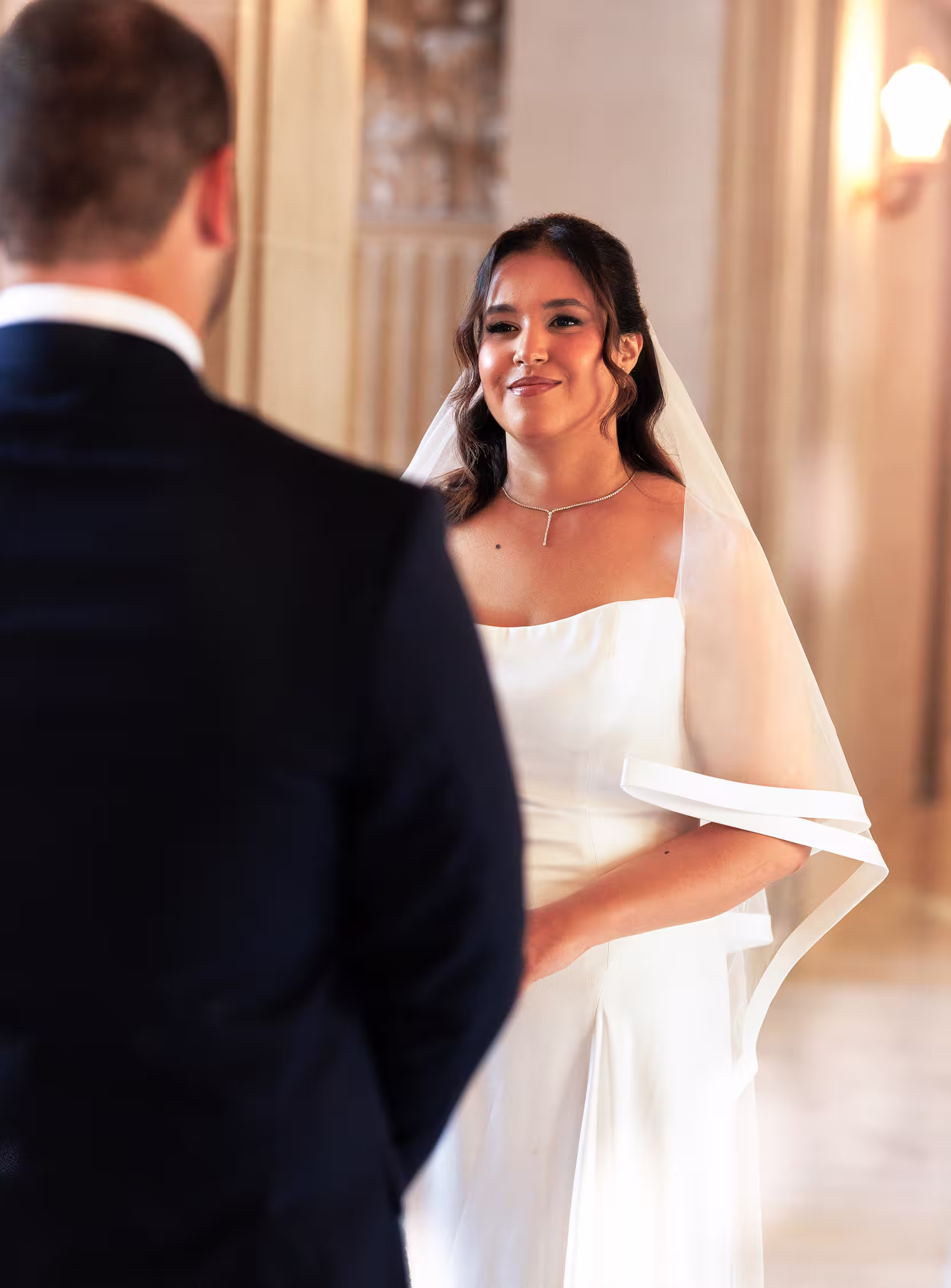 Bride smiling at her partner during their ceremony inside San Francisco City Hall, soft natural light and elegant modern wedding gown
