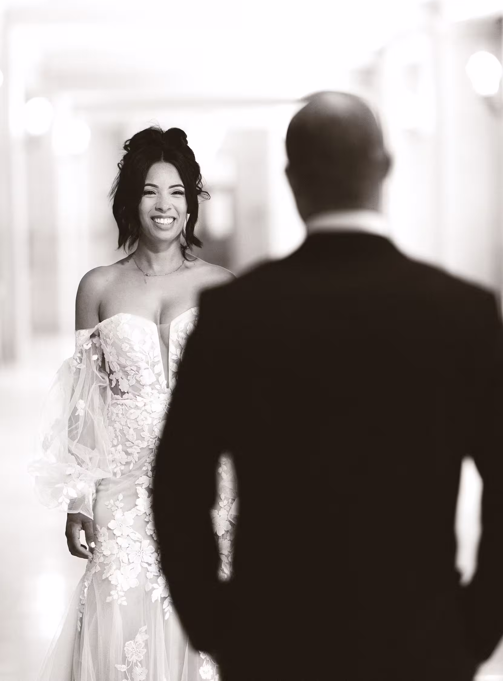 Bride smiling at her partner during a first look inside San Francisco City Hall, timeless black and white wedding moment with soft light