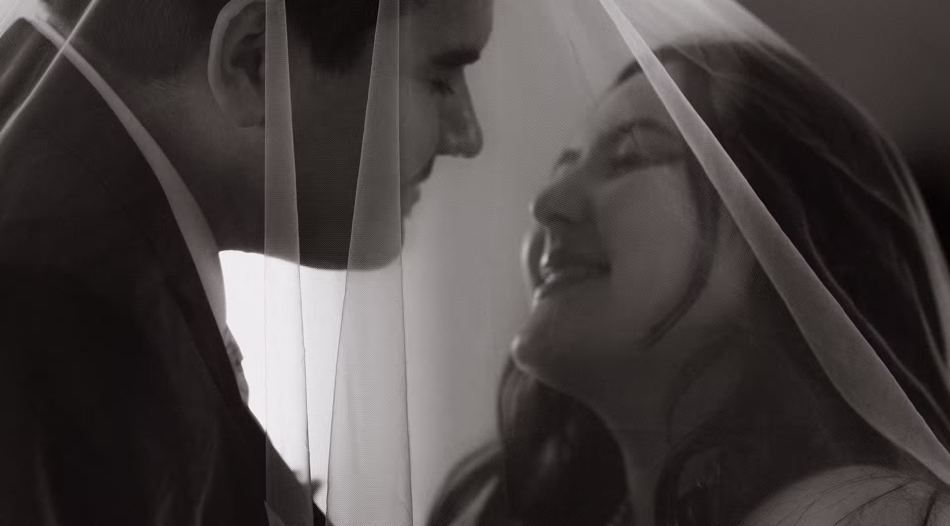 Bride and groom sharing an intimate moment under the veil inside San Francisco City Hall, soft romantic black and white wedding portrait