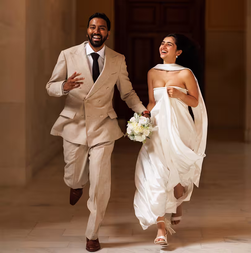 Joyful San Francisco City Hall wedding photo of newlyweds running together down the hallway