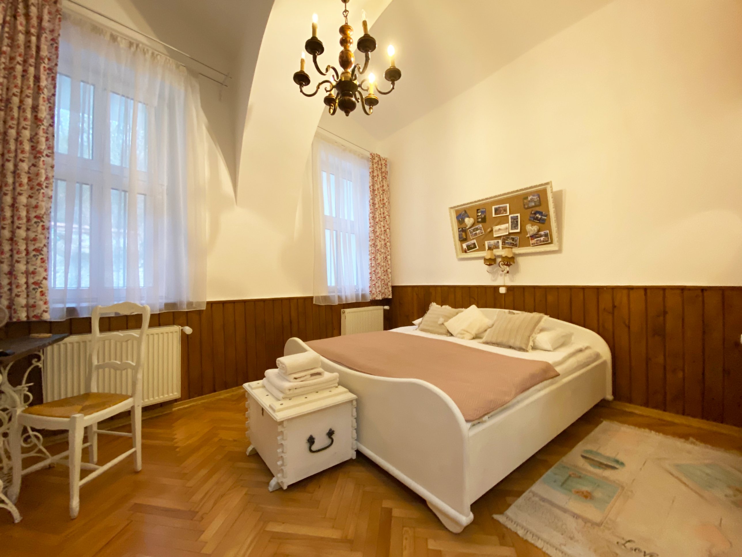 Dormitor cu tavan boltit și candelabru, într-un apartament din centrul istoric al Brașovului