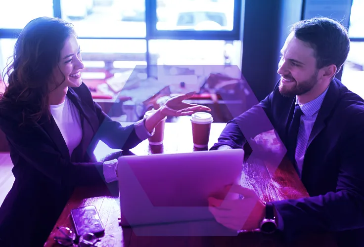 Stylized photo of 2 business people working on laptop in cafe