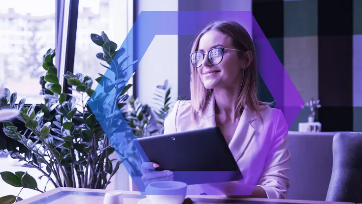 Young smiling businesswoman drinking coffee / tea and using tablet computer in a coffee shop