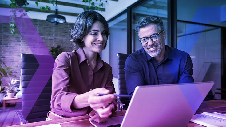 Business team of two executives working together using laptop in office.