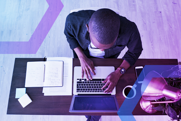 Top-down view of a professional working on a laptop, illustrating the need for modern browser security to protect against threats that legacy SWGs miss.