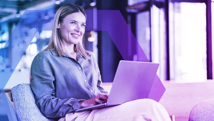 A professional woman works confidently on her laptop, representing a secure environment where initial access and phishing are prevented. The image symbolizes how Menlo HEAT Shield AI uses advanced AI to dynamically block zero-hour phishing attacks before they can cause harm.