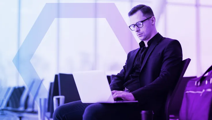 A professional works on a laptop in a modern office or travel lounge, representing the freedom and simplicity of Agentless Access. The image symbolizes seamless, secure access from any browser or device without the need for VPN hardware or client software