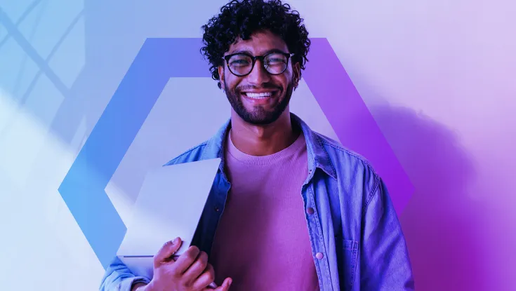 A smiling male tech professional with glasses and curly hair holds a closed laptop. The image is overlaid with a blue and purple color gradient and a large geometric hexagon, representing a secure and productive employee experience.