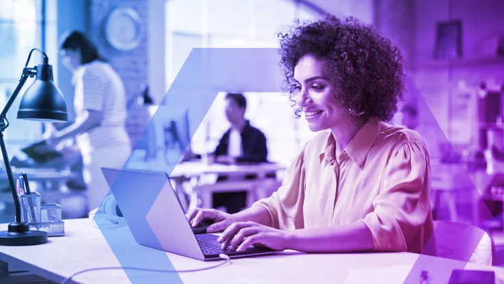 A female professional with curly hair smiles while working on her laptop in a busy office environment. A blue and purple geometric overlay frames the scene, illustrating seamless productivity and security in the modern workplace.