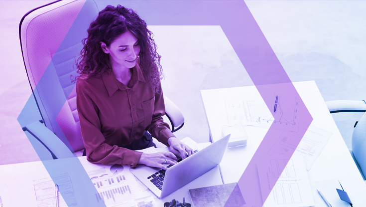 A high-angle view of a female professional with curly hair working on her laptop at a white desk. She is analyzing data charts and reports, demonstrating focused productivity in a secure environment, which is represented by a blue and purple geometric overlay.