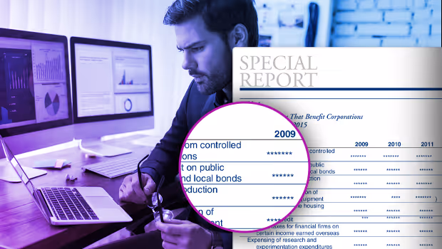 Man analyzing financial data on laptop with charts visible on two desktop monitors and a magnified section of a special report document.