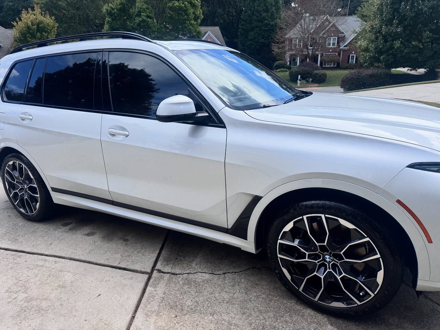 White BMW SUV parked on a driveway with black and silver alloy wheels and tinted windows.