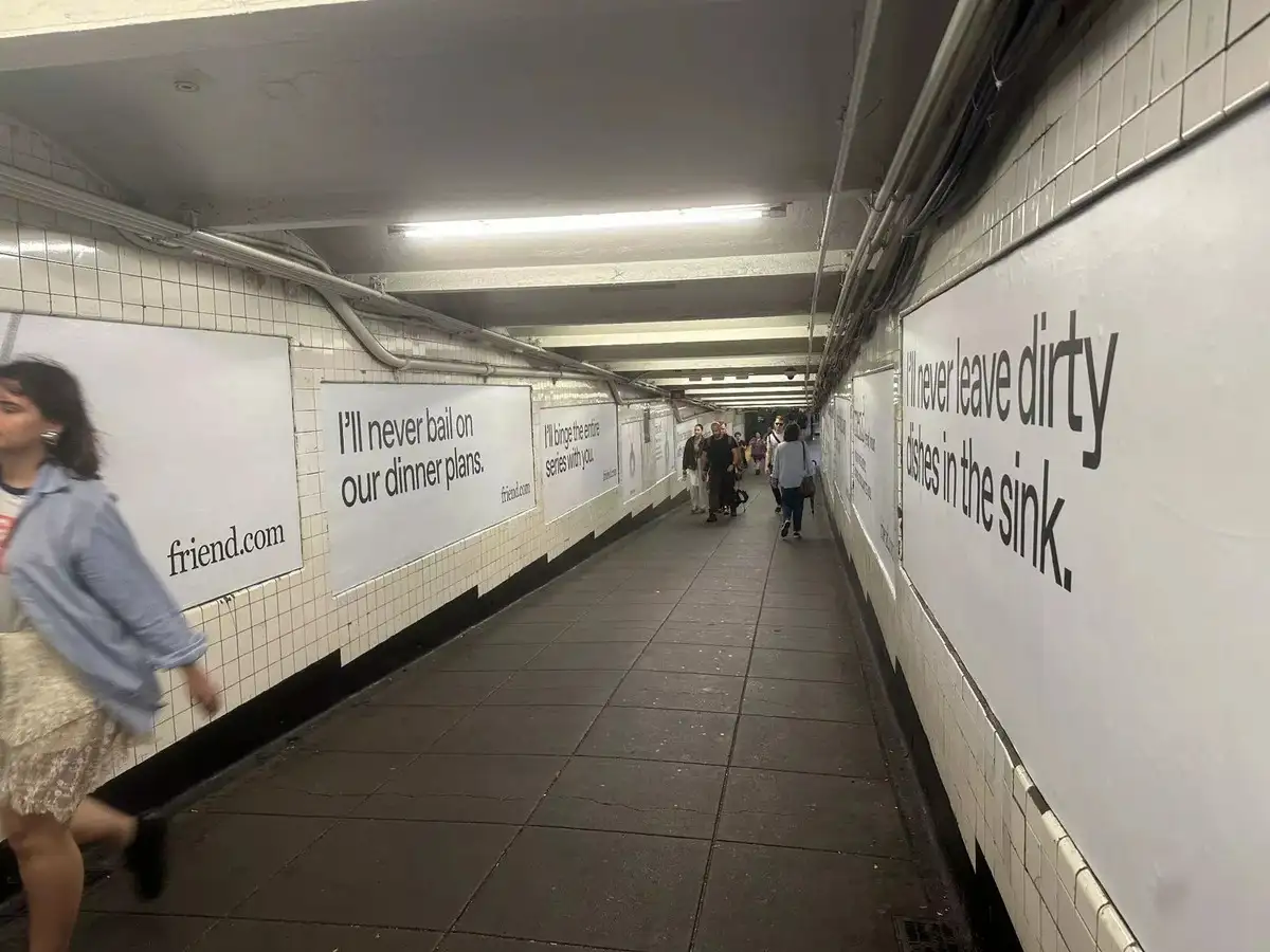 Photo of New York City subway passage covered with large white Friend ads featuring simple black text, including lines like “I’ll never bail on our dinner plans” and “I’ll never leave dirty dishes in the sink.” People walk through the corridor passing the large ads.