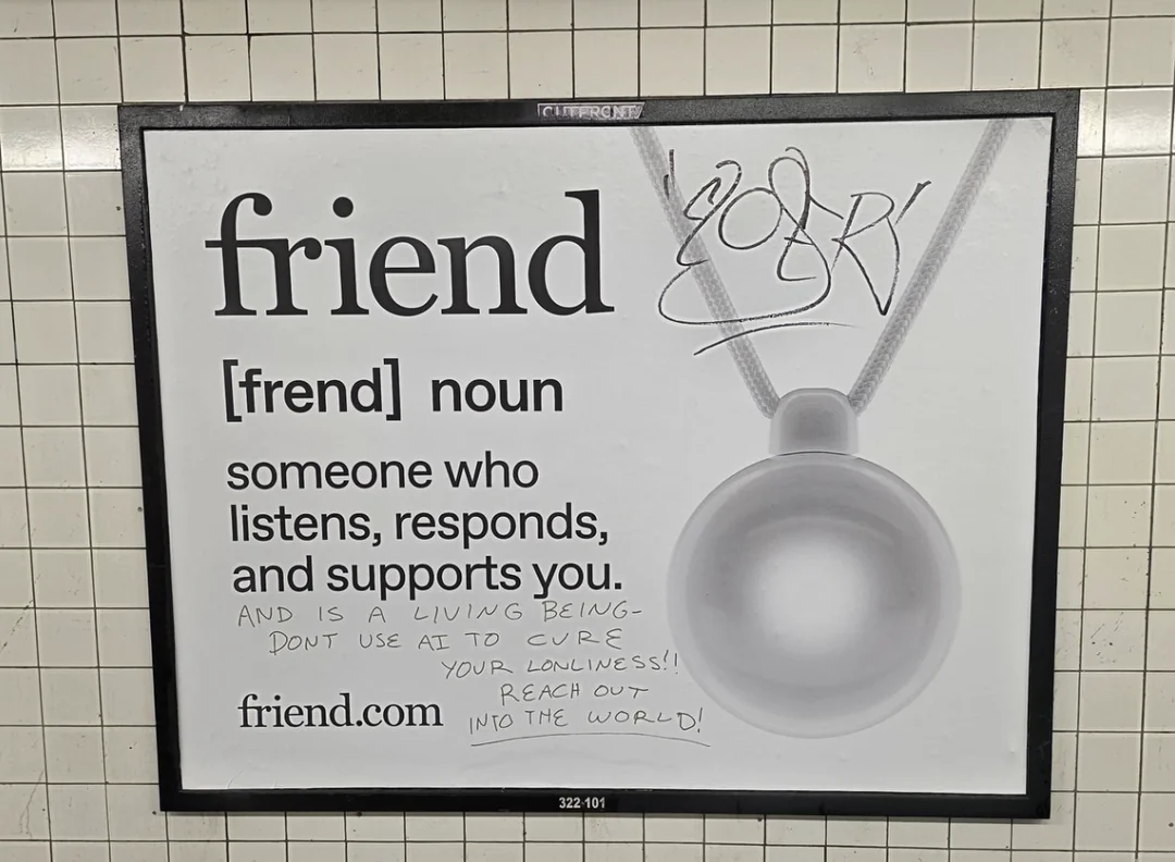 Photo of a Friend AI companion subway ad displaying the word “friend” with the pendant device pictured beside it. Someone has handwritten comments on the poster, including “[friend is...] a living being - don’t use AI to cure your loneliness!! Reach out into the world!”