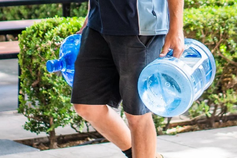 Delivery driver carrying two water cooler bottles