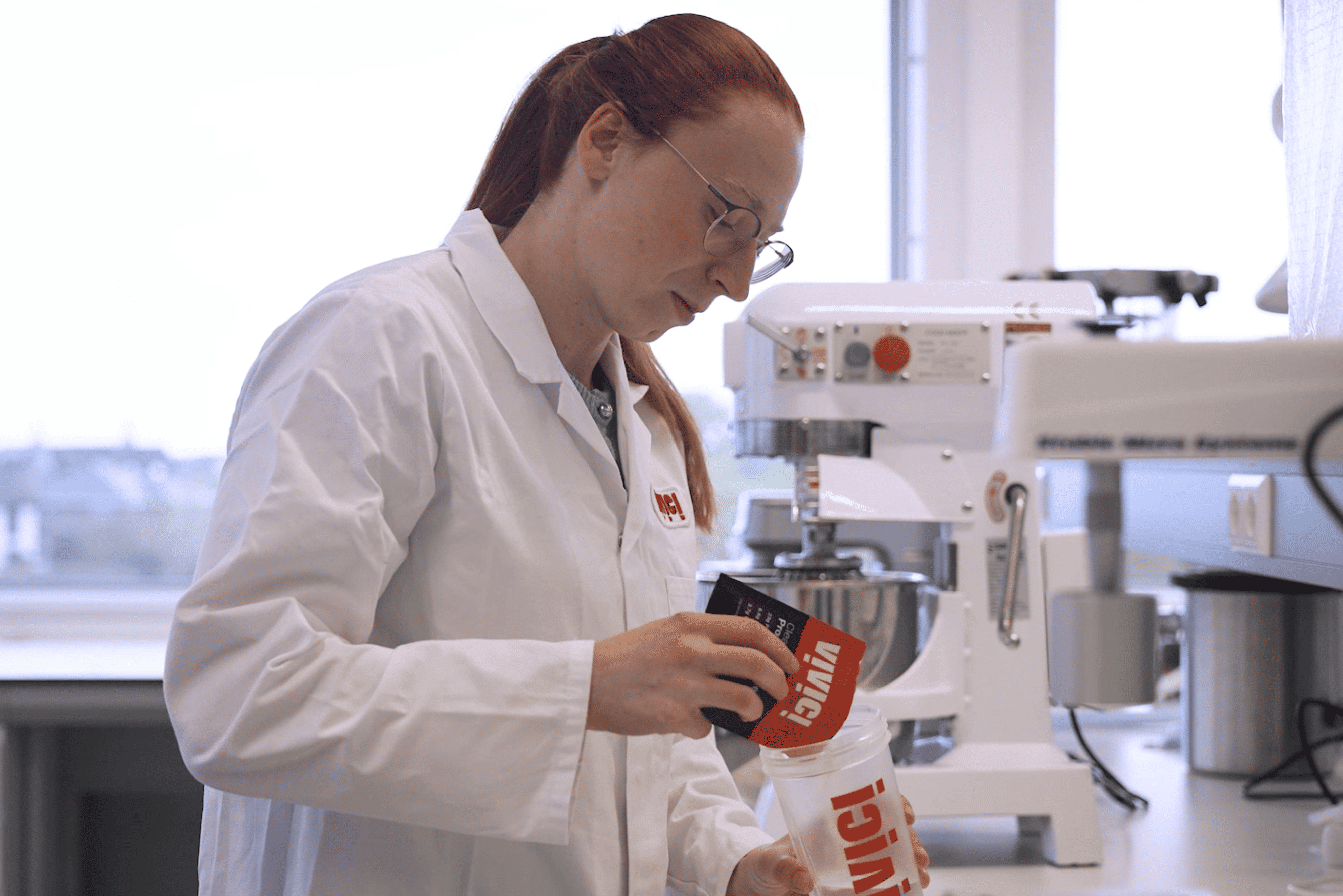 a woman with a white coat mixing vivici's ready-to-mix protein in a lab