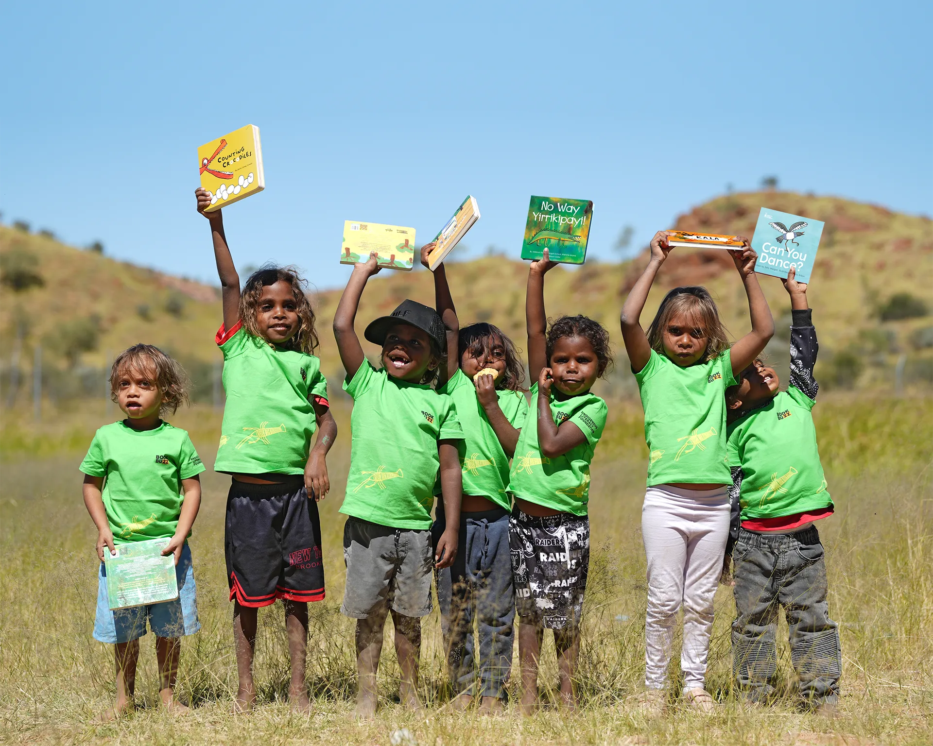 Be Part Of the Story - A group of kids in green ILF t-shirts holding up their favourite books on country.